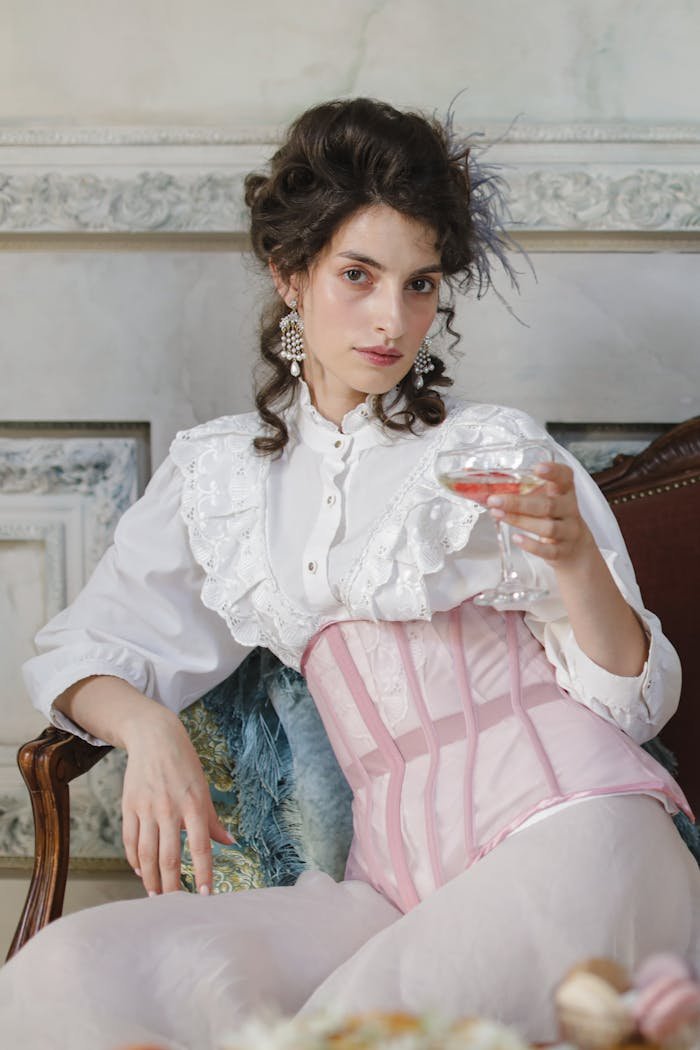 Portrait of a young woman in vintage fashion holding a cocktail indoors.