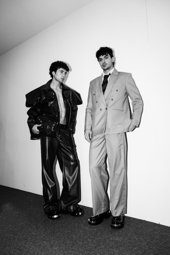 Two men in stylish suits showcase bold fashion design in black and white.