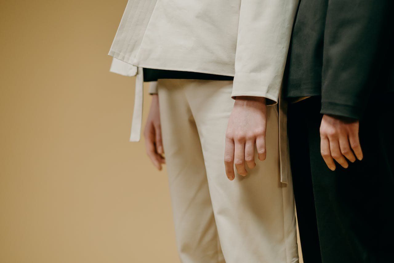 A minimalist fashion image showing models in long-sleeve outfits against a beige background.